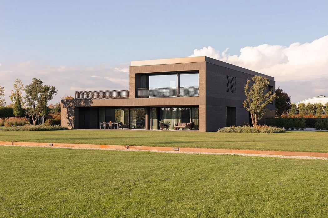 Modern two-story home with sleek black exterior, large windows, and a well-manicured lawn.