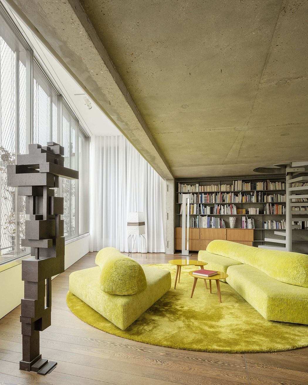 Minimalist living room with concrete walls, floor-to-ceiling windows, and vibrant yellow seating.