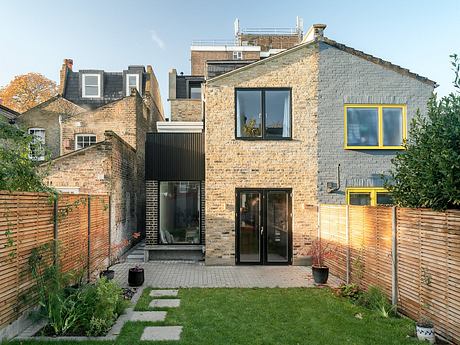 Contemporary brick home with large windows and a manicured garden.