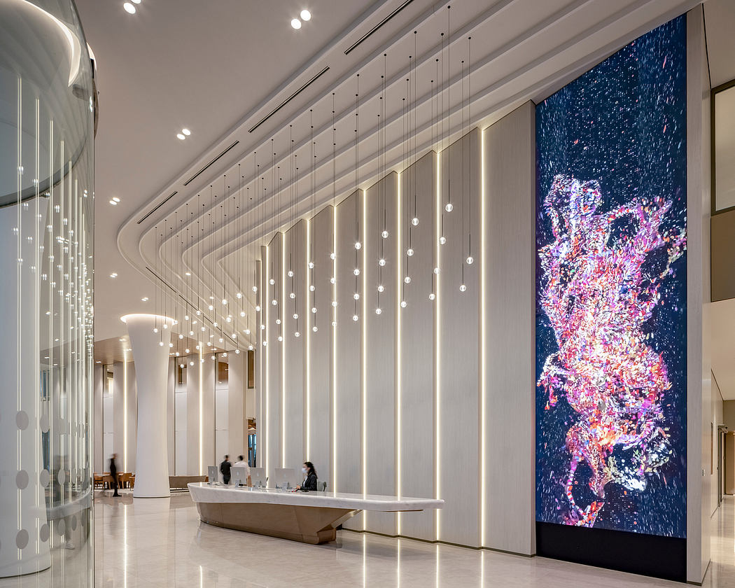 Modern lobby with curved ceiling, hanging lights, and large colorful digital art display.