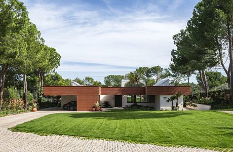 A modern single-story home with a prominent wooden awning and lush landscaping.