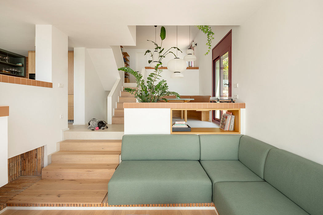 A modern open-concept living space with a wooden staircase, built-in shelves, and a green sofa.
