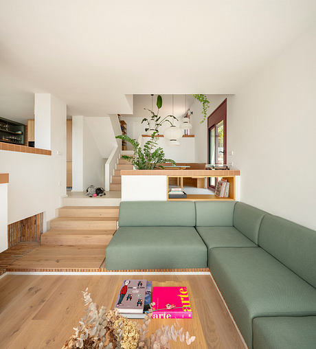 A modern open-concept living space with a wooden staircase, built-in shelves, and a green sofa.