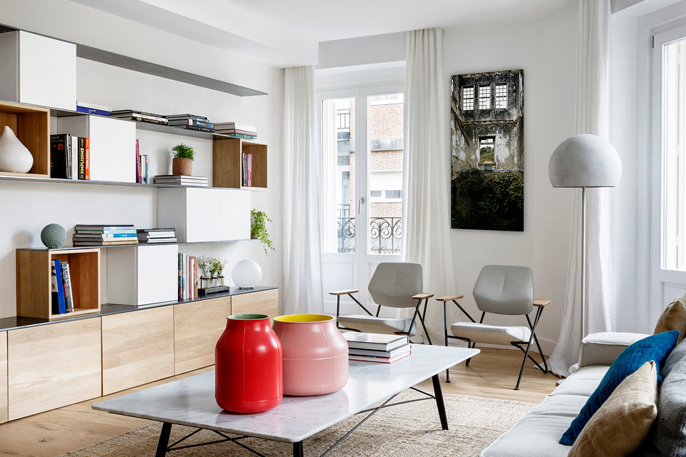 Bright, modern living room with sleek furniture and bookshelf.