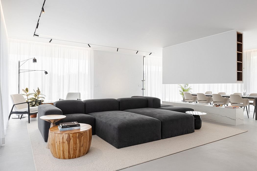 Minimalist living space with large, dark sofa and sleek white decor.