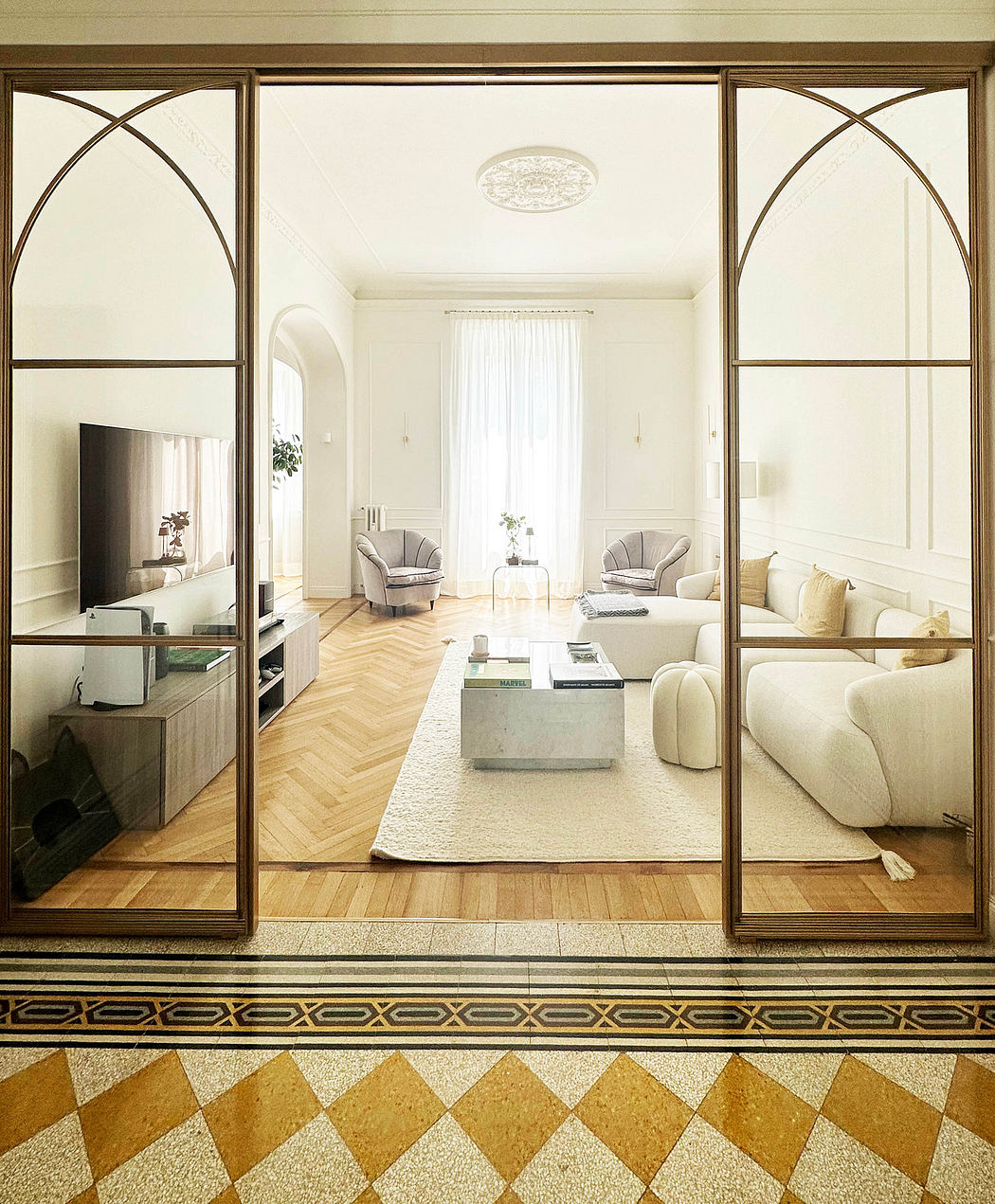 Elegant living room viewed through arched glass doors with patterned floor border.