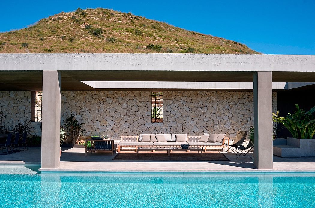 Modern outdoor patio with seating by a pool and stone wall background.