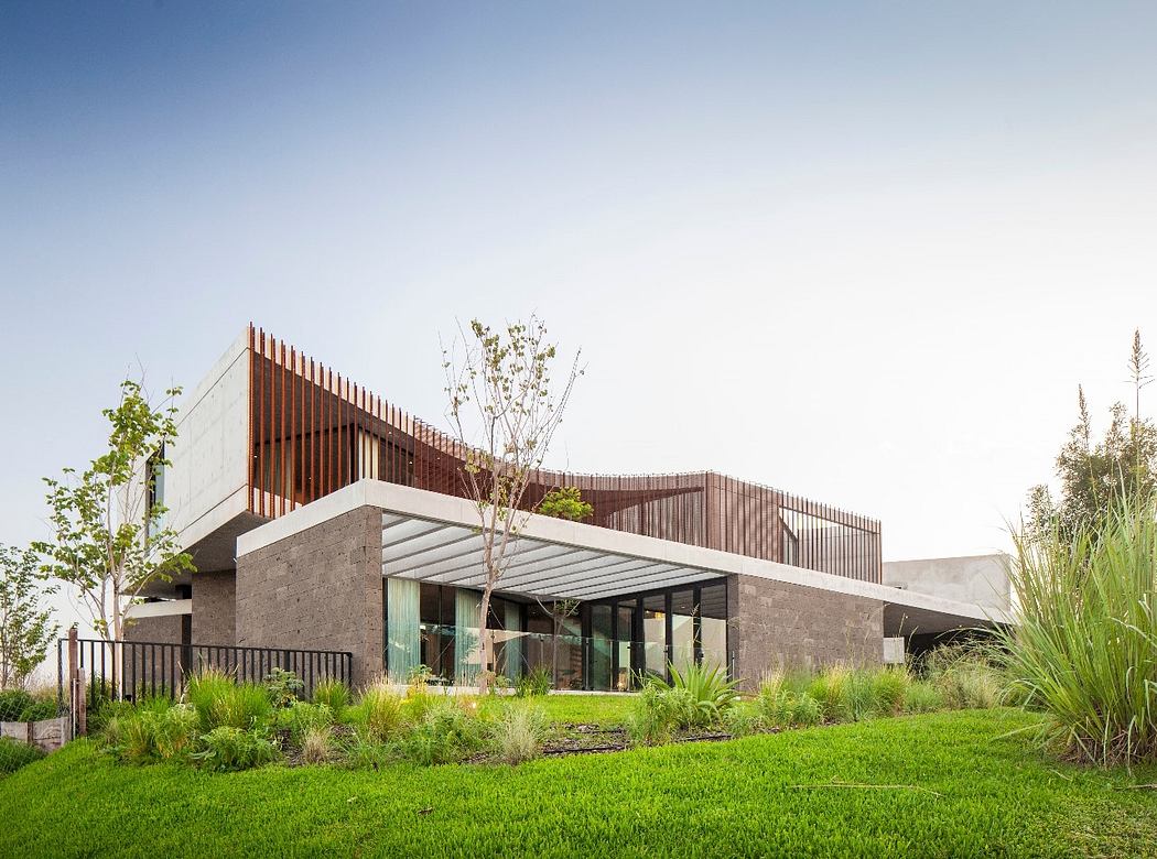 Modern house with geometric design and wooden slats surrounded by greenery.