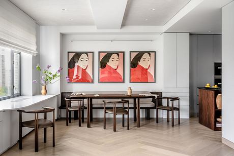 Clean, modern dining area with geometric artwork, minimalist furnishings, and sleek kitchen elements.