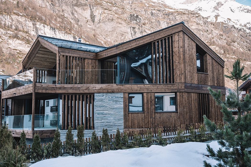 A rustic wooden lodge with a curved roof and large windows overlooking a snowy landscape.