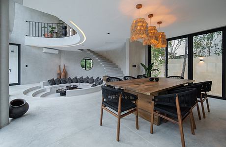 Modern dining room with wooden table, designer chairs, and a staircase leading to an