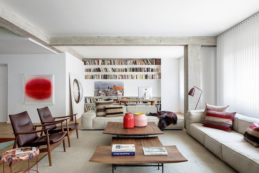 Airy, modern living space with built-in bookshelves, concrete beams, and eclectic furnishings.