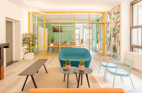 A vibrant, modern office space with colorful furniture, plants, and creative architectural elements.