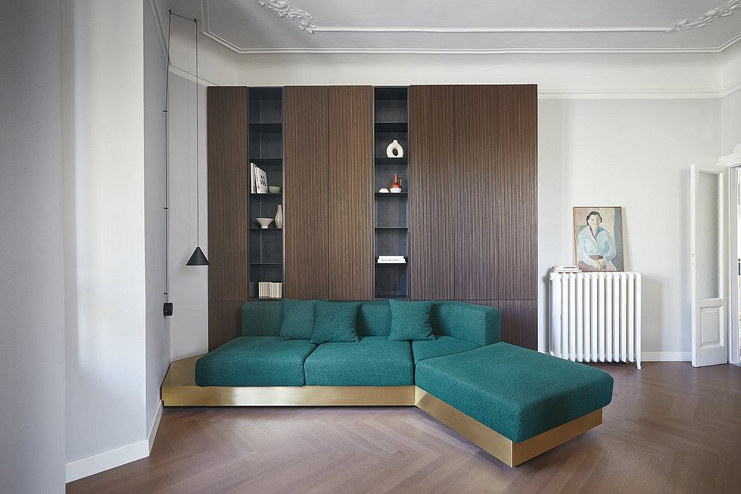A modern living room with a teal sectional sofa, built-in shelving, and a radiator.