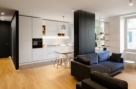 Modern living room with kitchen, white cabinetry, and a blue sofa.