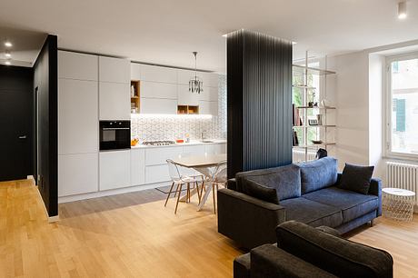 Modern living room with kitchen, white cabinetry, and a blue sofa.