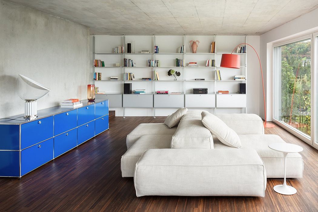 A modern living room with a white sofa, blue storage unit, and floor-to-ceiling bookshelves.