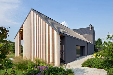 Contemporary gabled house with vertical wood siding and lush garden.