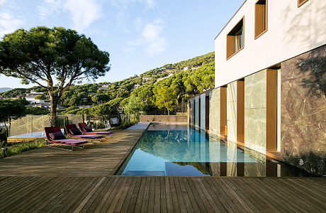 The image depicts a modern villa with a sleek, minimalist design. The pool and surrounding deck create a serene outdoor living space.