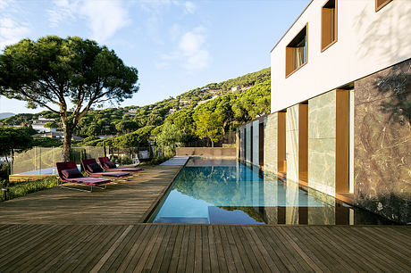 The image depicts a modern villa with a sleek, minimalist design. The pool and surrounding deck create a serene outdoor living space.