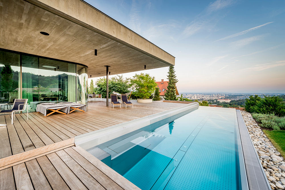 Modern house terrace with infinity pool and city view.