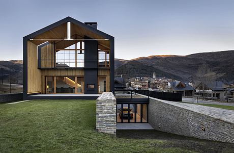 A modern, wooden and stone architectural design with clean lines and large windows offering scenic mountain views.