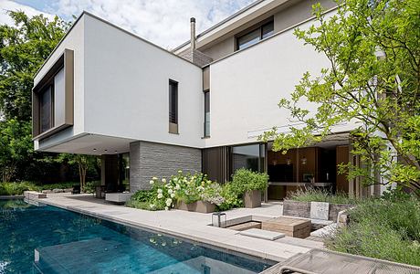 A modern, multi-level home with a sleek exterior, lush landscaping, and a tranquil pool.