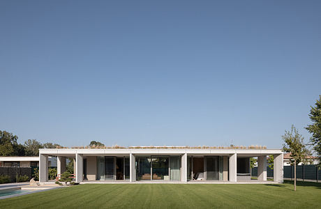 Modern single-story house with large windows and flat roof on a green lawn.