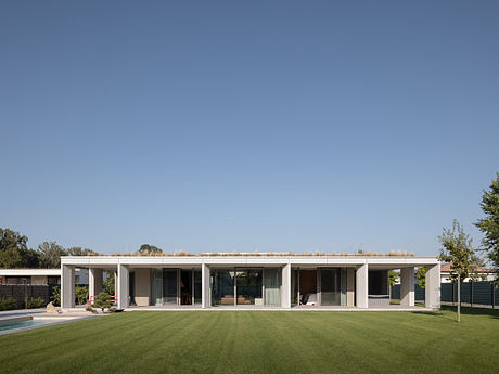 Modern single-story house with large windows and flat roof on a green lawn.