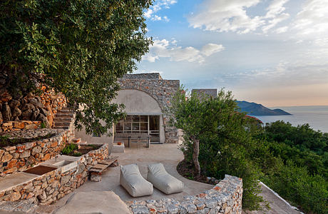 Scenic stone terrace with cushioned seating, overlooking lush greenery and ocean view.