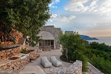 Scenic stone terrace with cushioned seating, overlooking lush greenery and ocean view.