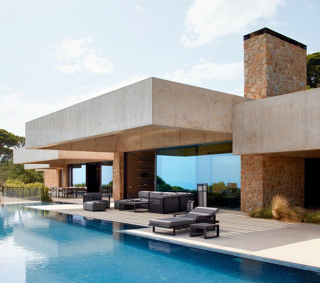 Contemporary house with poolside lounge area and expansive glass windows.