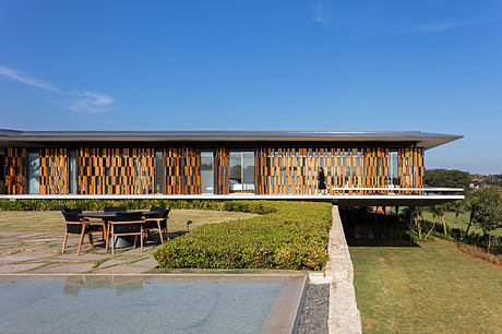 Modern single-story building with a striking orange and brown facade, surrounded by lush greenery.