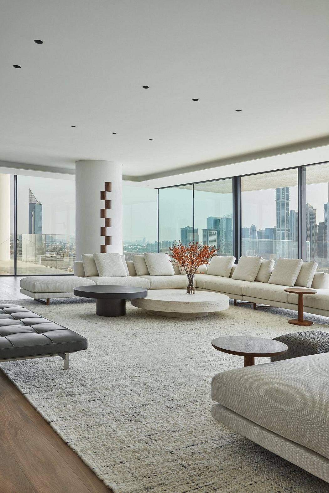 Spacious modern living room with sleek furniture, floor-to-ceiling windows, and a cityscape view.