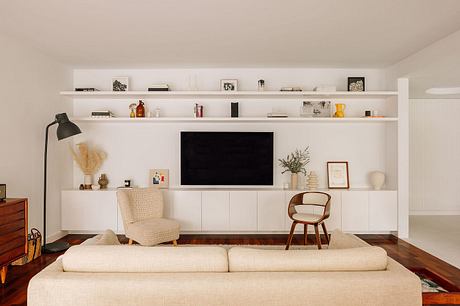 Minimalist living room with built-in shelving, midcentury-inspired furniture, and wooden floors.