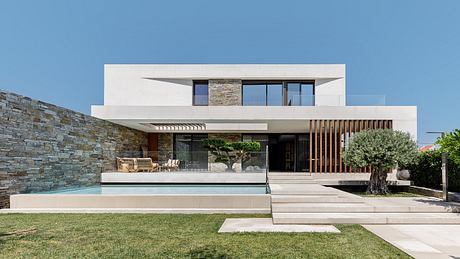 Modern minimalist building with stone walls, glass facade, and private pool.