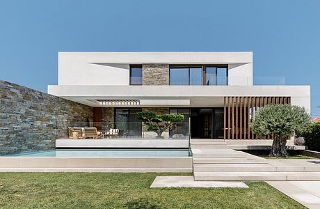 Modern minimalist building with stone walls, glass facade, and private pool.