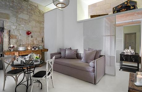 Rustic stone walls, modern furniture, and vintage decor create a cozy, eclectic living space.