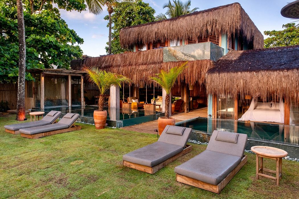 Lush tropical villa with thatched roof, wooden decking, and outdoor pool areas.