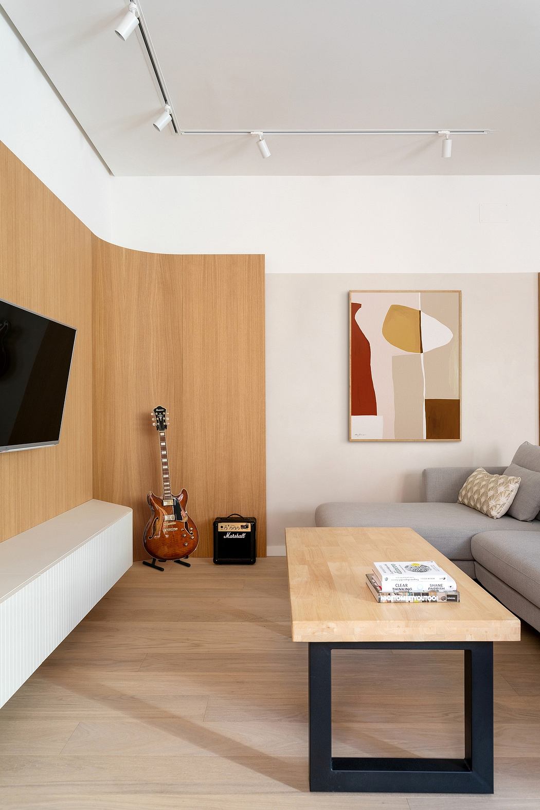 Minimalist living room with wooden walls, abstract artwork, and a sleek coffee table.