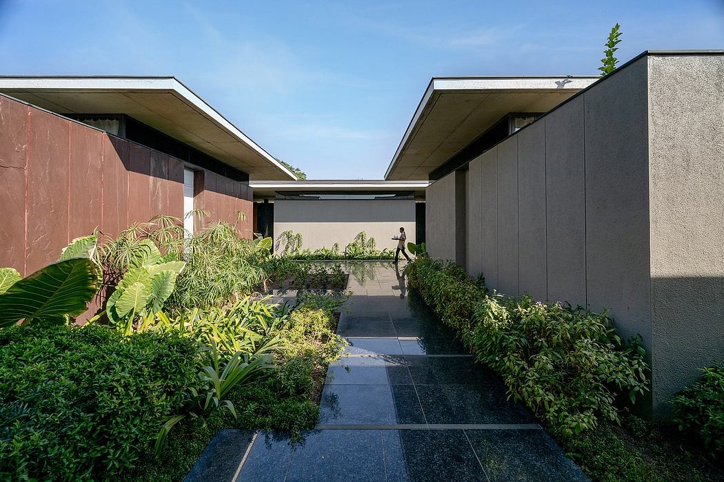 A modern courtyard with lush vegetation, slate tiles, and minimalist architecture.