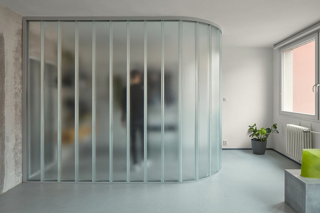 Curved glass partition dividing the room, creating a modern, minimalist aesthetic.