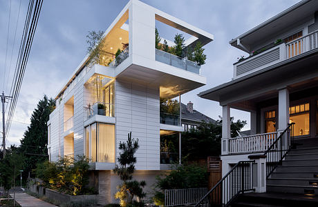 Modern architectural design with cantilevered balconies, glass walls, and outdoor lighting.