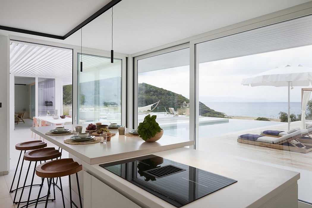 Sleek, minimalist kitchen with floor-to-ceiling glass walls showcasing stunning ocean view.