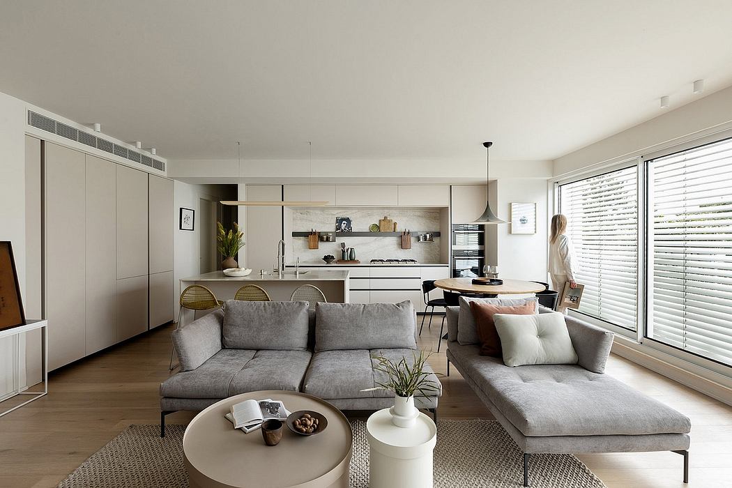 Bright, minimalist open-concept living space with contemporary furniture, kitchen, and large windows.