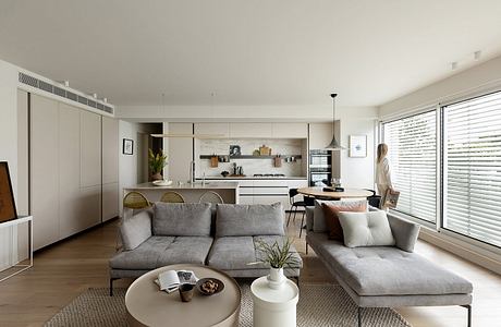 Bright, minimalist open-concept living space with contemporary furniture, kitchen, and large windows.