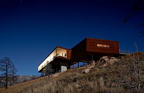 Contemporary hillside house with expansive windows at twilight.