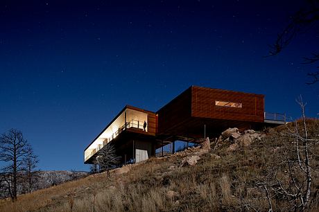 Contemporary hillside house with expansive windows at twilight.