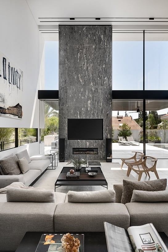 Minimalist living room with large stone fireplace, open plan, and panoramic windows.