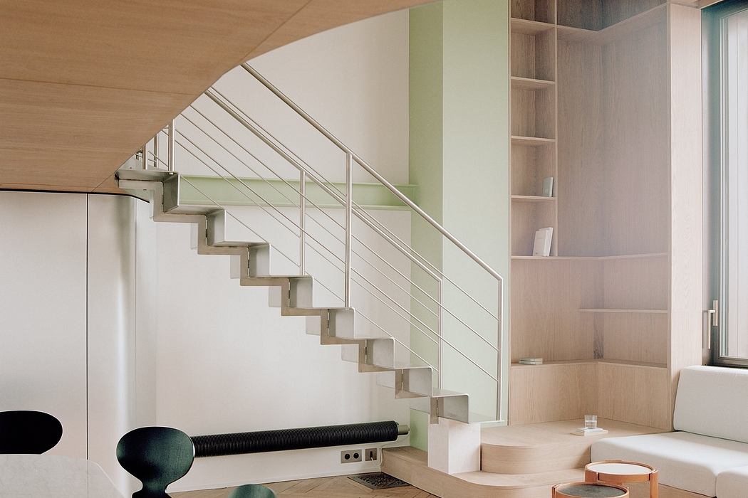 Modernist staircase with steel railing and built-in shelving in open-concept living space.
